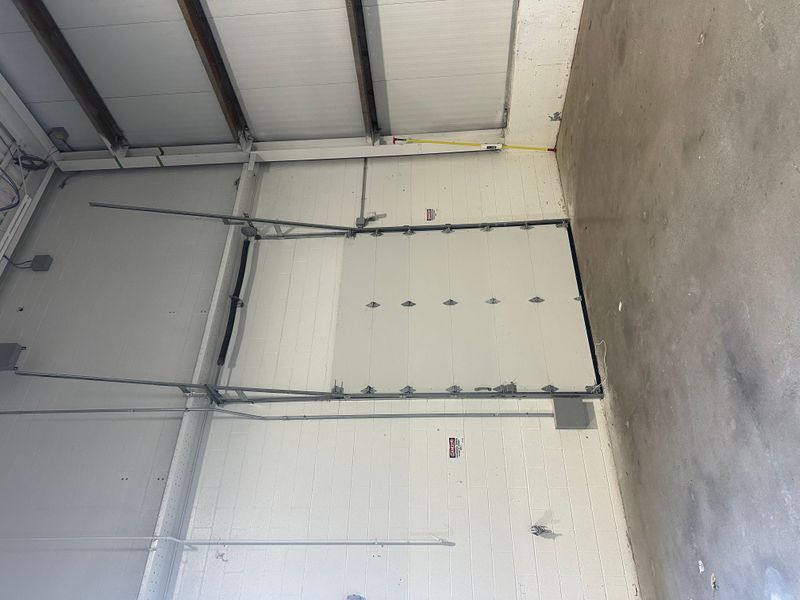 Large commercial insulated sectional door interior with track hardware and spring system
